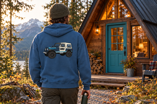 person wearing the blue jeep renegade back hoodie outside a wooden a-frame cabin with a turquoise door